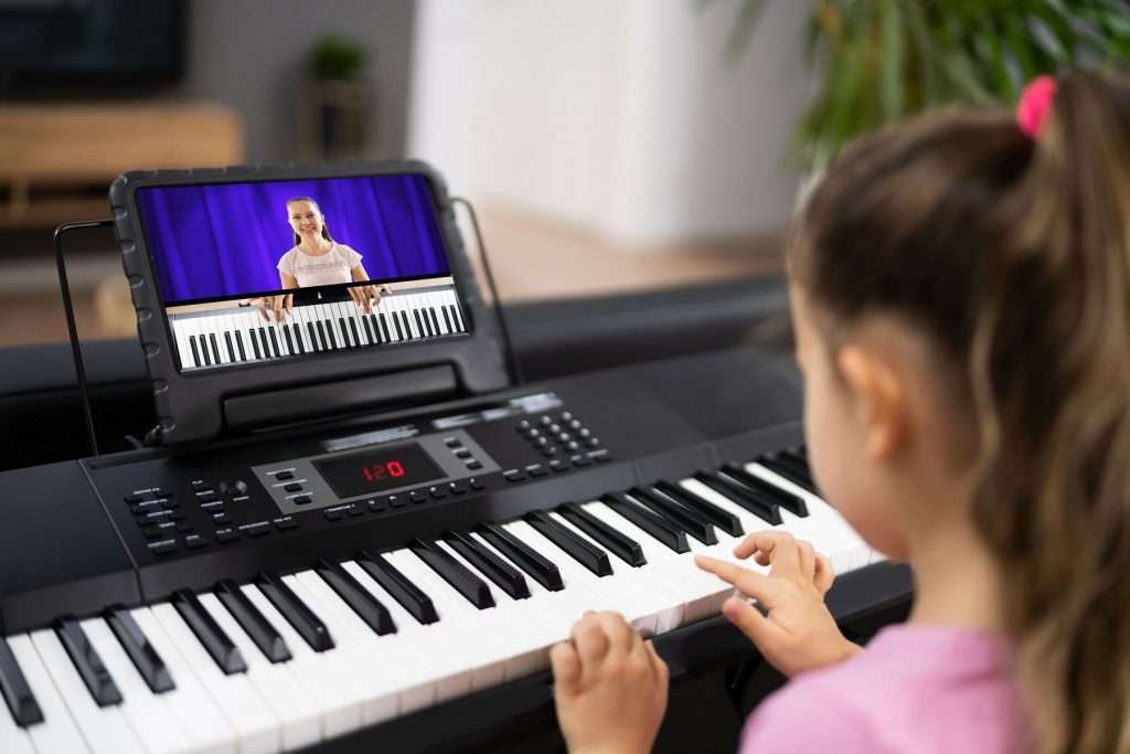 A female kid learning piano through a tutorial video