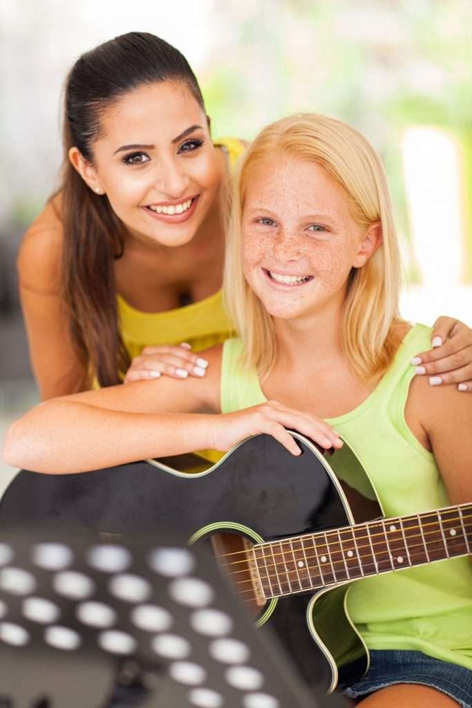 guitar instructor and her young student smiling at the camera