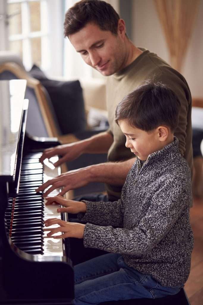 male piano instructor teaching his young boy student